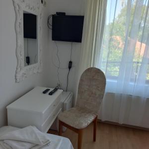 a room with a chair and a desk and a television at хотел Кристиан in Sozopol