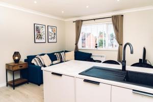 Lovely one bedroom apartment COLCHESTER في Mile End: مطبخ وغرفة معيشة مع أريكة زرقاء