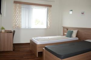 1 dormitorio con 2 camas y ventana en Hotel Khail, en Maria Lanzendorf