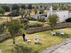 Um homem está a cortar a relva num quintal em Masseria Palombara Resort & SPA - Adults only em Manduria