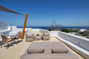 a patio with a table and chairs on a balcony at I K I A Since 1980 by Calm Collection in Fira