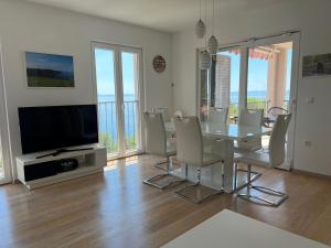 a dining room with a table and chairs and a television at Apartament Sunny z obłędnym widokiem na morze in Baška Voda