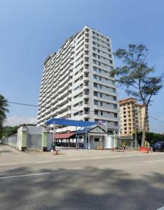 a large white building with a blue canopy in a parking lot at NurIzz Condostay Homestay Pantai Puteri Melaka in Kampong Bukit Darat