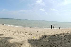a group of people walking on the beach at NurIzz Condostay Homestay Pantai Puteri Melaka in Kampong Bukit Darat