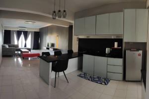 a kitchen with a counter and a living room at NurIzz Condostay Homestay Pantai Puteri Melaka in Kampong Bukit Darat