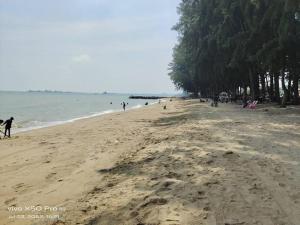 a beach with a lot of people and the ocean at NurIzz Condostay Homestay Pantai Puteri Melaka in Kampong Bukit Darat