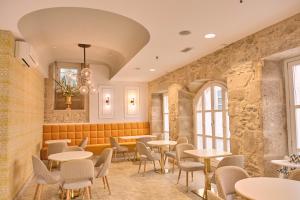 a restaurant with tables and chairs and a stone wall at Hotel Praza Quintana in Santiago de Compostela