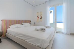 a white bedroom with a bed with towels on it at Villa Paschalia,Sea View, Pool, Gym, Sleeps 10 in Mikonos +100 photos