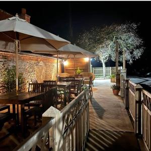 an outdoor patio with tables and umbrellas at night at The Boot and Shoe Inn in Flintham