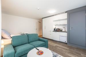 a living room with a green couch and a kitchen at Modern Studio and good located in Frankfurt/Main