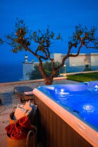a swimming pool with a tree in the background at Villa Mimina - Exclusive villa with garden, Jacuzzi and sea view in Praiano