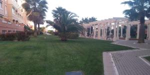 une cour verdoyante avec des palmiers et un bâtiment dans l'établissement Isla Canela Apartamento nuevo en primera línea de playa con vistas al mar, à Isla Canela