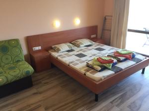 1 dormitorio con 1 cama y 1 silla verde en къща за гости Каланджа 2 en Sinemorets