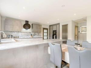 a white kitchen with a counter and chairs in it at Willows Cottage in Blackburn