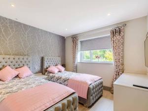 a bedroom with two beds and a window at Willows Cottage in Blackburn