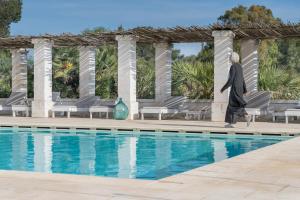 a swimming pool with a blue chair and a blue umbrella at Masseria Palombara Resort & SPA - Adults only in Manduria