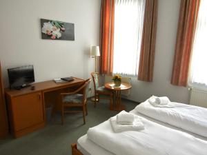 a hotel room with two beds and a desk at Pension Hexenkessel in Wernigerode