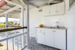 a kitchen with white cabinets and a balcony at Kalogeraki Studios in Potos