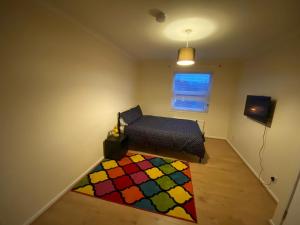 a bedroom with a bed and a colorful rug on the floor at Home away from home with fantastic spacious rooms in Abbey Wood