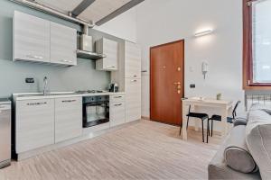 a kitchen with white cabinets and a table and a couch at Honey Loft [Milano-Como-Svizzera] in Seregno