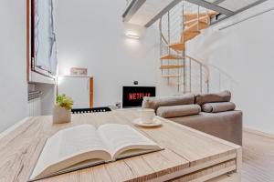 uma sala de estar com uma mesa com um livro aberto em Honey Loft [Milano-Como-Svizzera] em Seregno