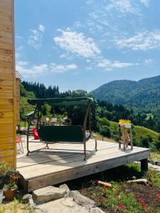 a bench on a deck with a view of a mountain at Mitarbi Silence - cozy holiday cottages in mountains in Borjomi