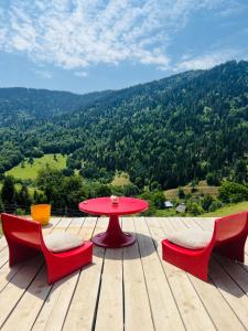 a red table and two chairs on a wooden deck at Mitarbi Silence - cozy holiday cottages in mountains in Borjomi