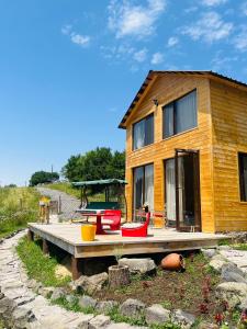 a wooden house with a picnic table on a deck at Mitarbi Silence - cozy holiday cottages in mountains in Borjomi