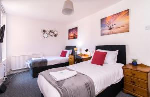 a hotel room with two beds and a night stand at Characterful 2 bed apartment - Spacious & Comfy in Castle Donington