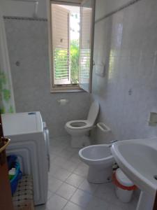 a white bathroom with a toilet and a sink at Villa Gelsomino in Mongiove