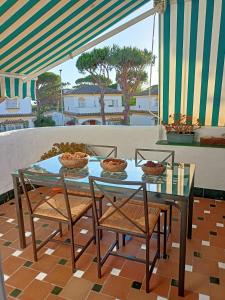 een glazen tafel met stoelen en kommen eten op een patio bij Pueblo Marinero in Novo Sancti Petri