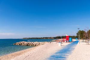 a sandy beach next to the water with a pier at Apartment Imela in Pula
