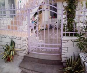Biała brama do domu z roślinami w obiekcie Villa Anna w mieście Tríkeri
