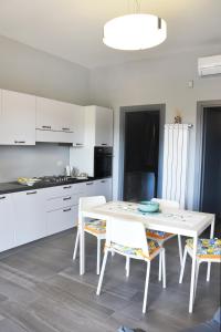a white kitchen with a white table and chairs at AA Residence - free private parking in Sarno