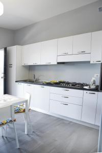 a white kitchen with white cabinets and a table at AA Residence - free private parking in Sarno