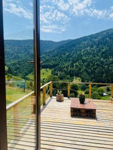 a wooden deck with a table and a view of the mountains at Mitarbi Silence - cozy holiday cottages in mountains in Borjomi