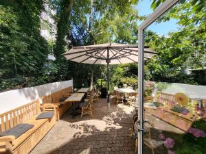 un patio con bancos, sombrilla y mesas en Aussen Alster Hotel, en Hamburgo