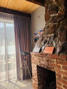 a camera in a room with a stone fireplace at Mitarbi Silence - cozy holiday cottages in mountains in Borjomi