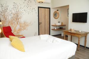 ein Schlafzimmer mit einem weißen Bett, einem Schreibtisch und einem Fernseher in der Unterkunft SensUP à 5min de Pairi Daiza in Brugelette