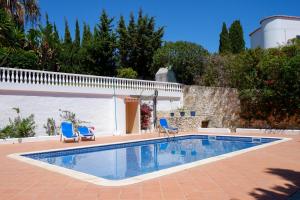 una piscina con 2 sillas azules y una casa en Casa Carioca Carvoeiro, en Carvoeiro