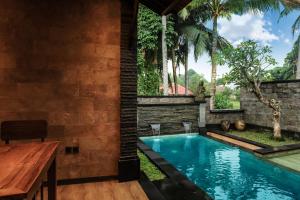 uma piscina numa casa com uma mesa de madeira e cadeiras em Villa Emerald: Precious Find in the Central Ubud em Ubud