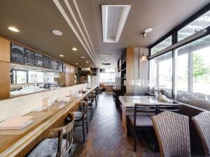 un comedor con mesas, sillas y ventanas en Tabist Diversity Hotel Sin Tokiwa Asahikawa en Asahikawa