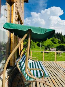 a chair with a green umbrella sitting on a deck at Mitarbi Silence - cozy holiday cottages in mountains in Borjomi