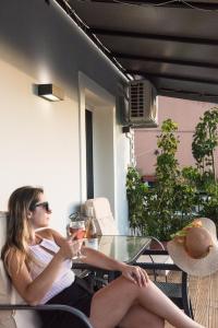 a woman sitting at a table with a glass of wine at Boboli Holiday House Acharavi Corfu in Acharavi