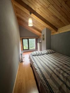 a bedroom with a large bed with a wooden ceiling at Mitarbi Silence - cozy holiday cottages in mountains in Borjomi