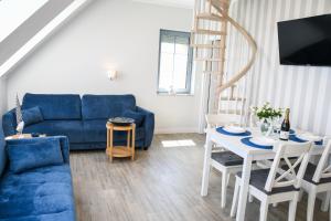 a living room with a blue couch and a table at Apartamenty Wrzosowa in Dębki