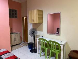 a kitchen with green chairs and a table and a fan at Bilik Harian Pengkalan Chepa in Pengkalan Cepa