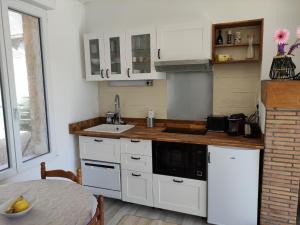eine Küche mit weißen Schränken, einer Spüle und einem Tisch in der Unterkunft Détente au bord du Loir - Gîte 2 in Les Roches-lʼÉvêque
