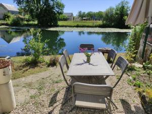 uma mesa e cadeiras em frente a um lago em Détente au bord du Loir - Gîte 2 em Les Roches-lʼÉvêque