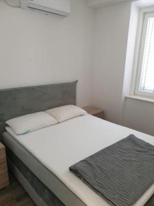 特里班的住宿－Apartmani Sain Tribunj，卧室配有白色床和灰色床头板